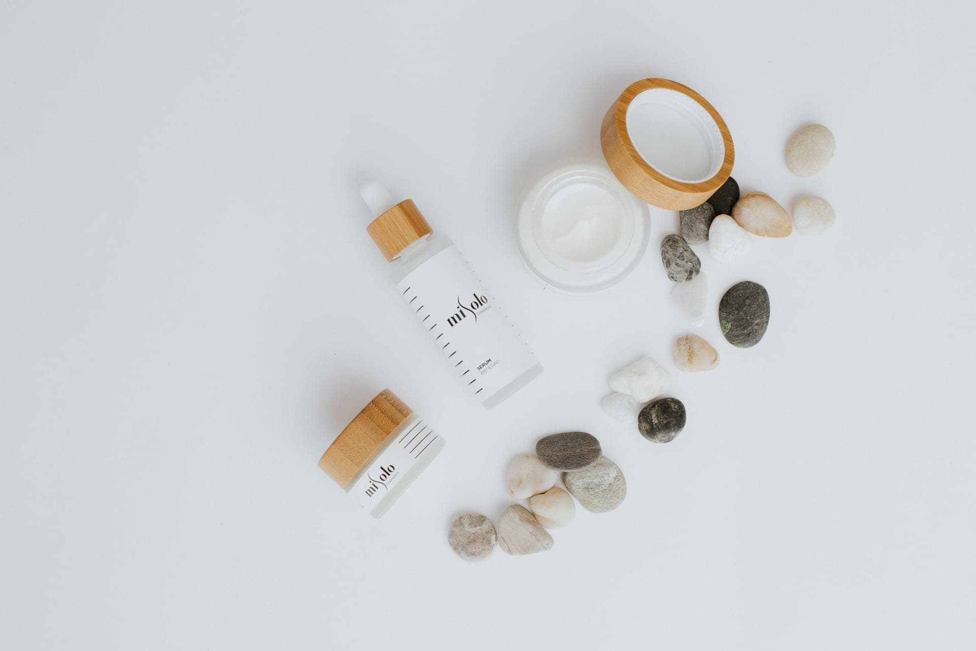 A flat lay of plain skincare bottles and jars on a white background