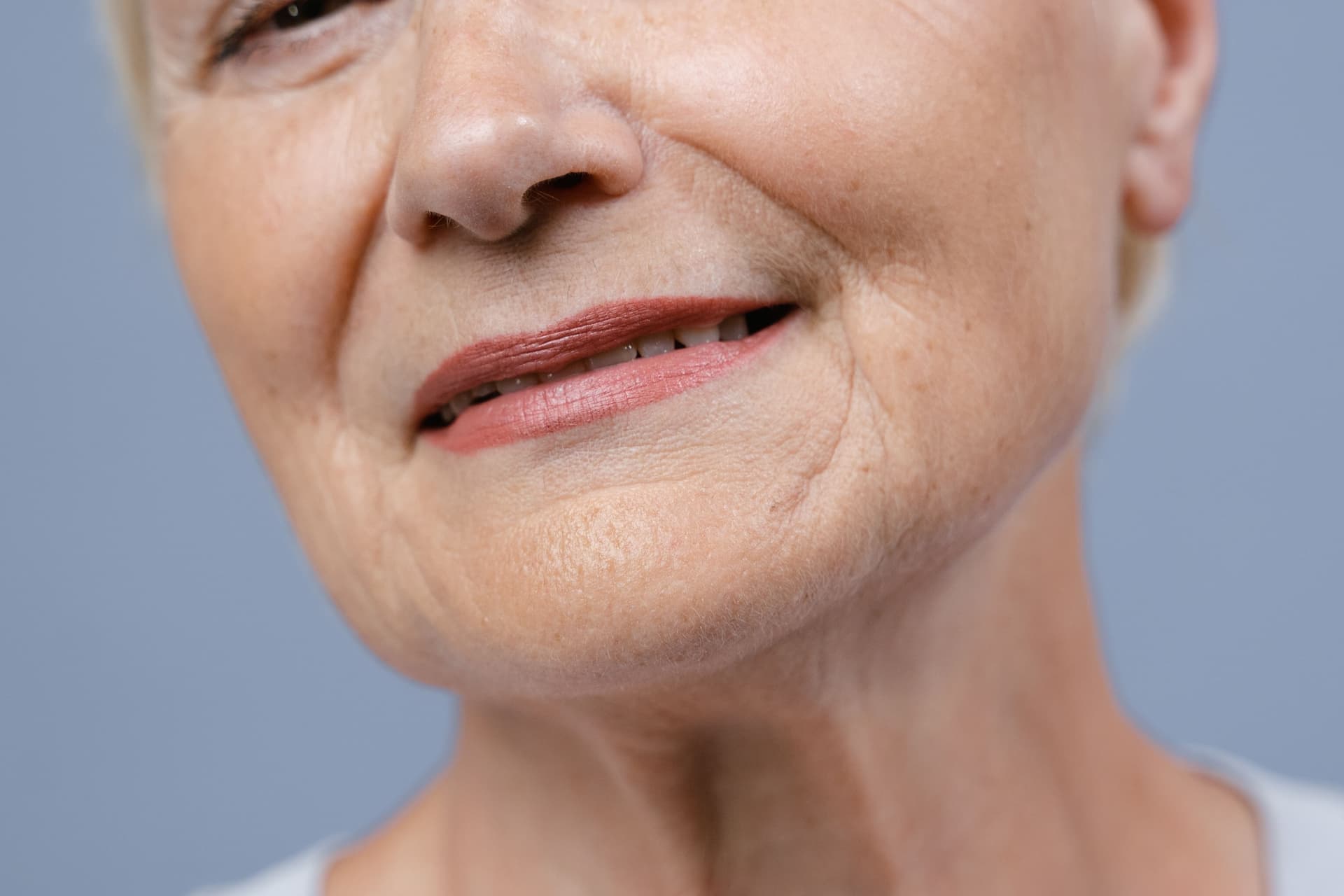 Close detail of an older woman's mouth and skin, showing natural lines and texture