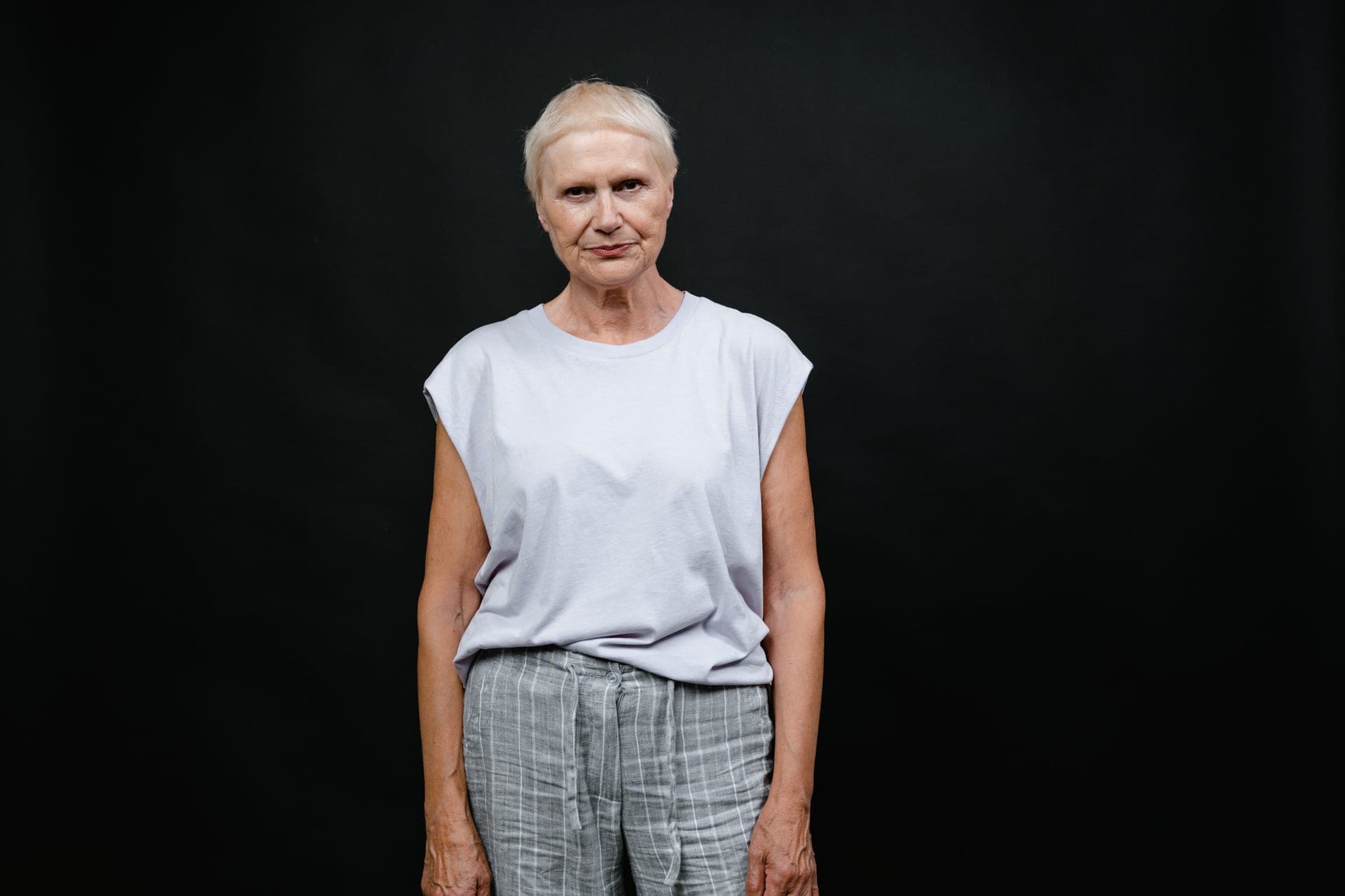Portrait of a senior woman in a casual outfit against a dark plain background