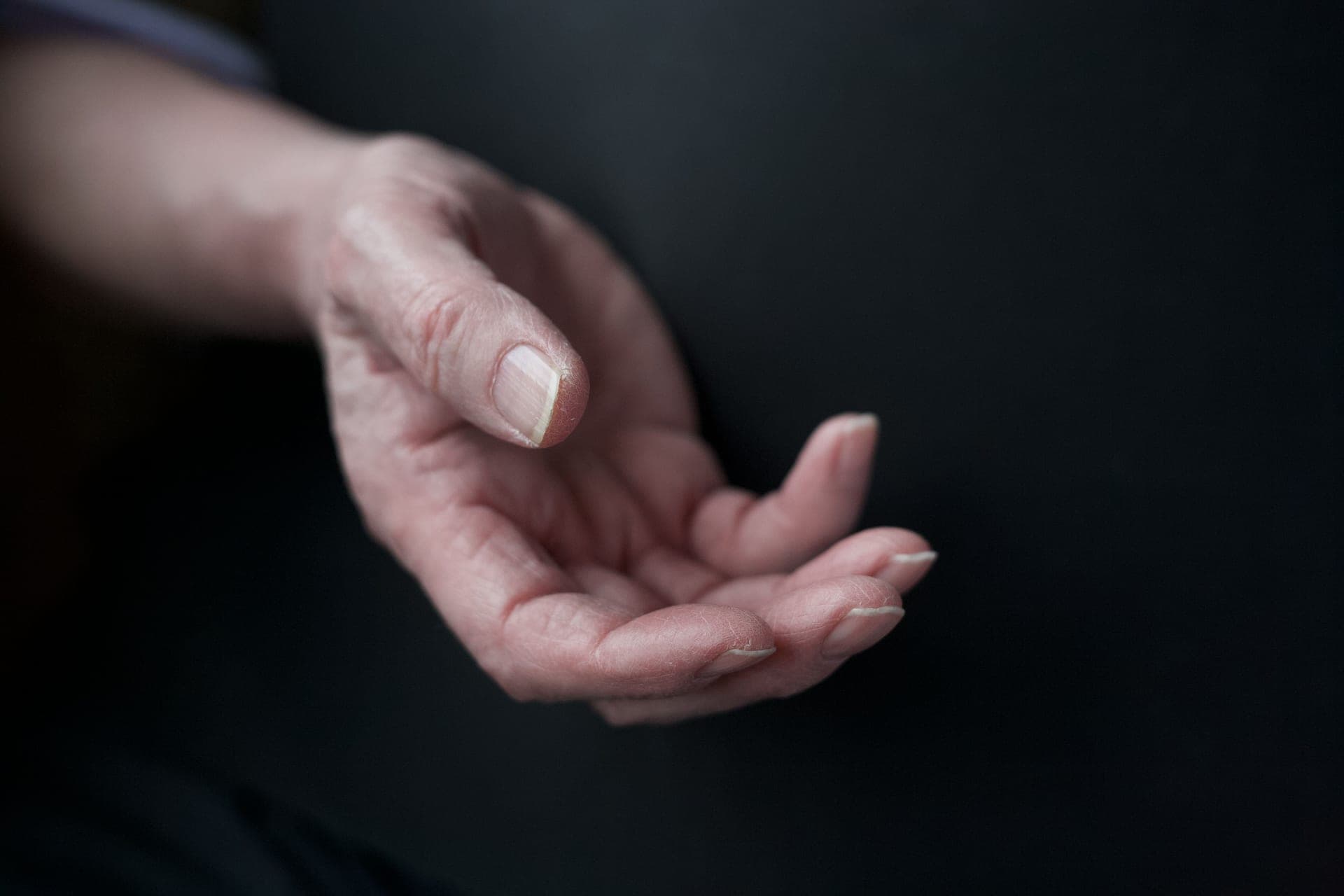 Close-up of an elderly hand against a dark background