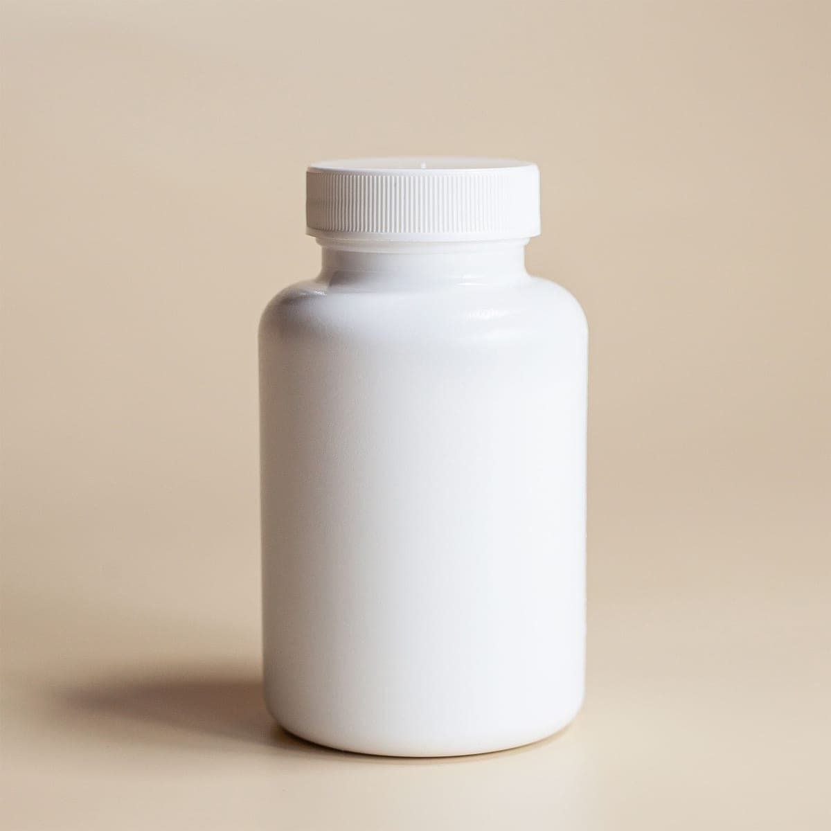 A plain white cosmetic bottle on a neutral beige background